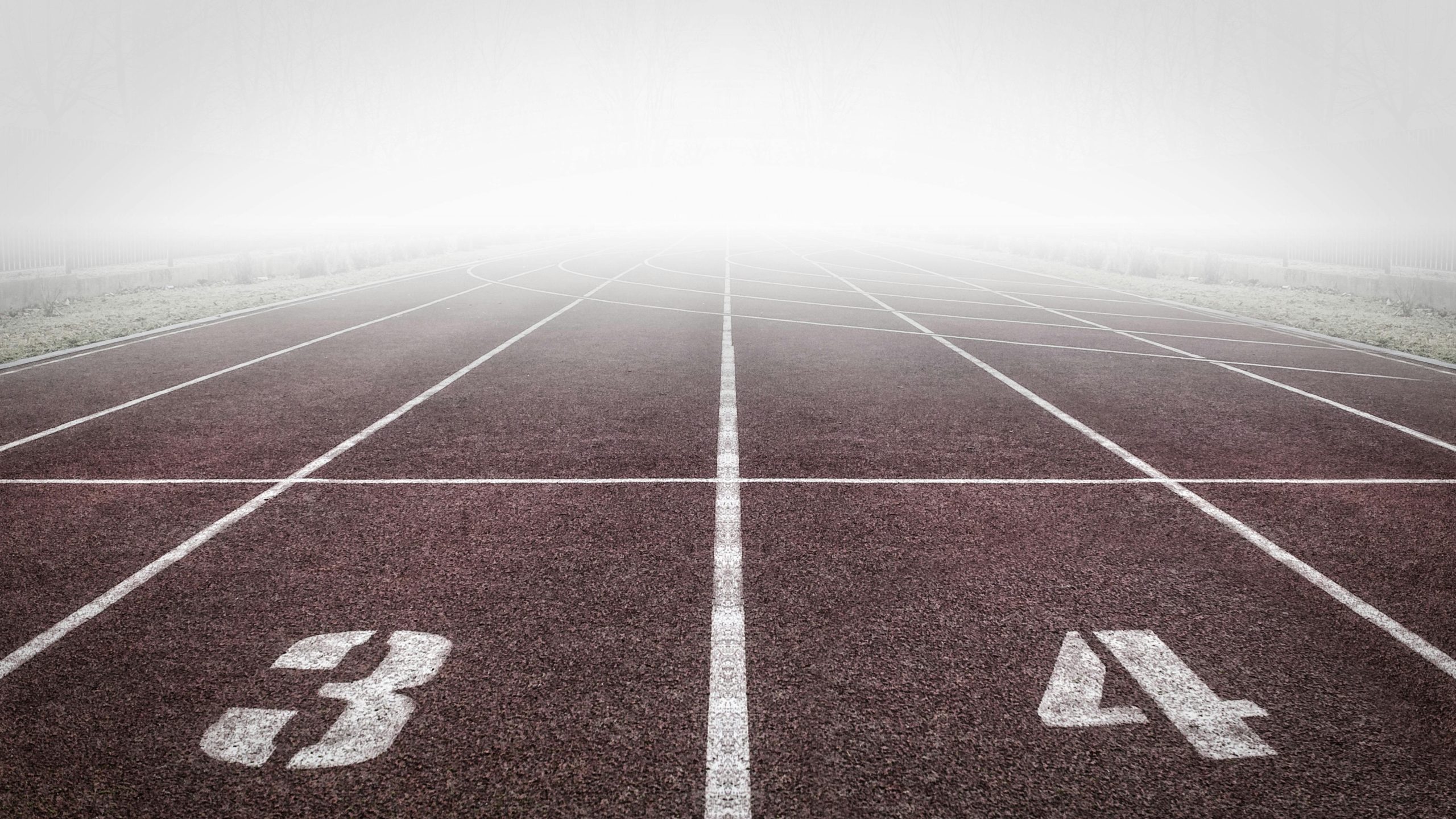 A foggy track field with visible lane numbers and white lines.