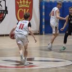 Gracz UJK z numerem 11, Dominik Wesołek, rusza z piłką w lewej ręce na kosz drużyny AZS AGH Kraków