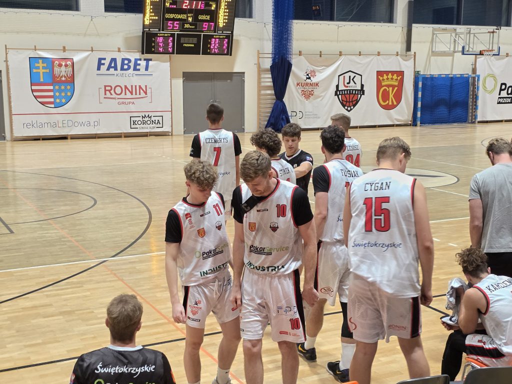 Rozczarowani gracze drużyny UJK Kielce, w centrum Marek Pisarczyk, kapitan drużyny, po lewej stronie Dominik Wesołek, również z głową spuszczoną w dół, po prawej tyłem stoi Norbert Cygan, w tle reszta drużyny: Adam Strojek, Stanisław Strojek, Maciej Flisiak, Mateusz Czemerys i Oskar Lesisz, na ławce siedzi Filip Karczemny.